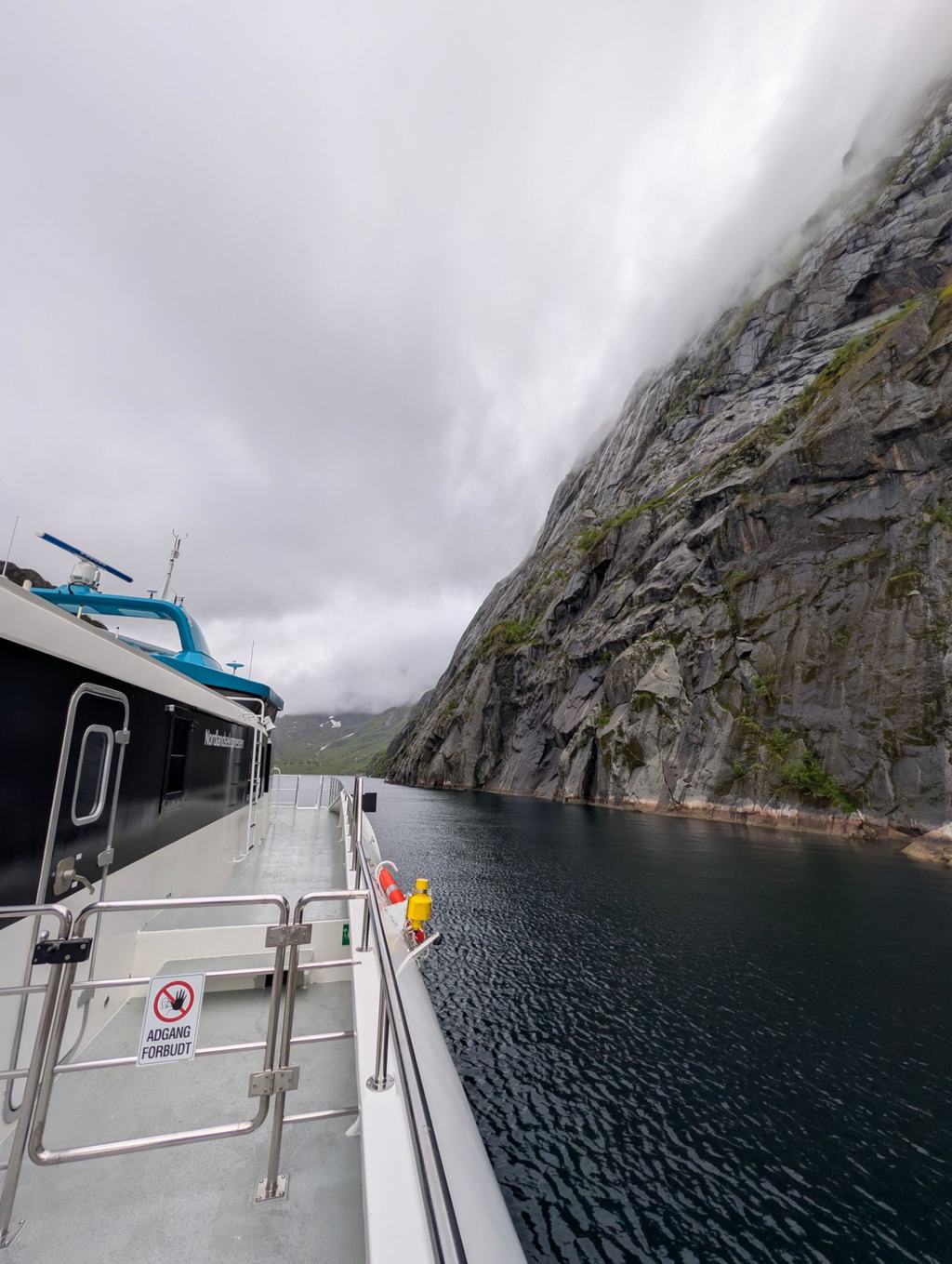 Utsikt fra dekk på Nordlandsekspressen i en smal fjord med tåke